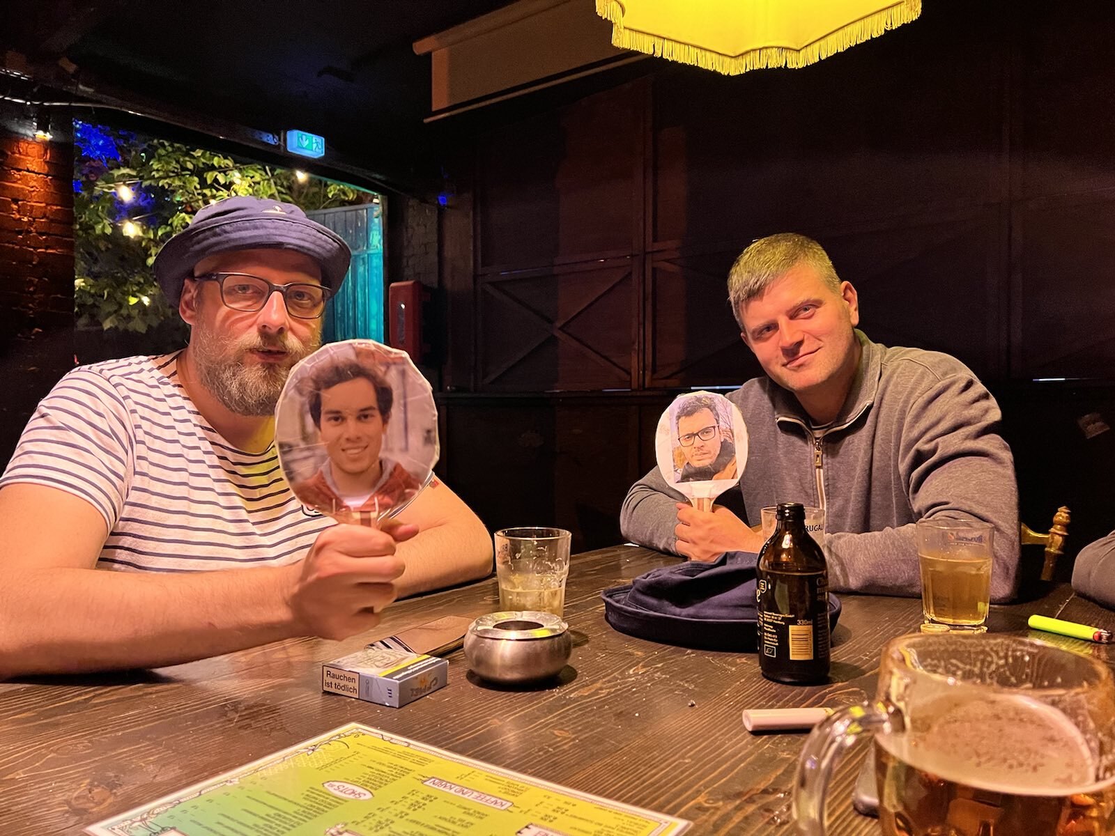 AJ and Tim holding up ping pong paddles with Marius and Abdul's faces on.